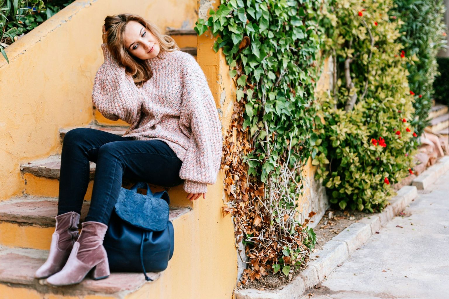 Blonde woman wearing cashmere sweater and sitting on yellow steps